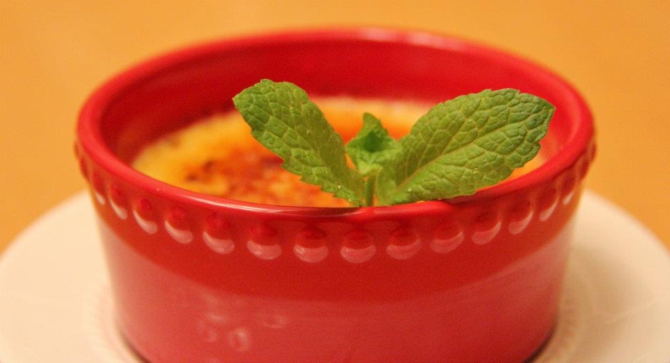 Crème brûlée in a red ramekin with fresh mint