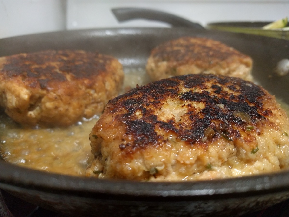 Chicken or turkey cutlets frying golden in a cast iron pan