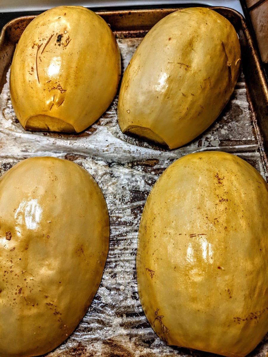 Halved roasted spaghetti squash on a baking sheet